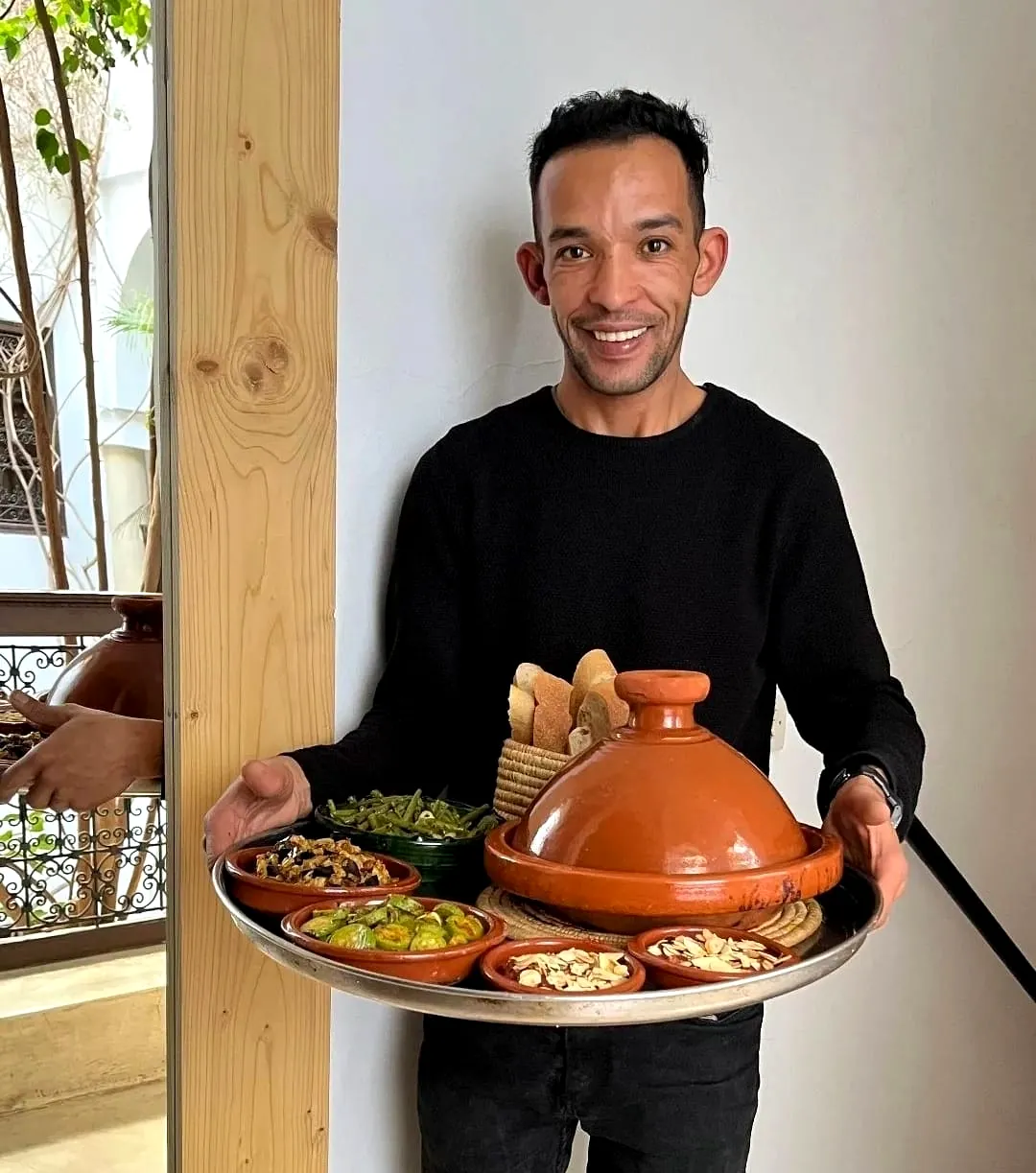Chef serving a tagine with Moroccan salads and bread