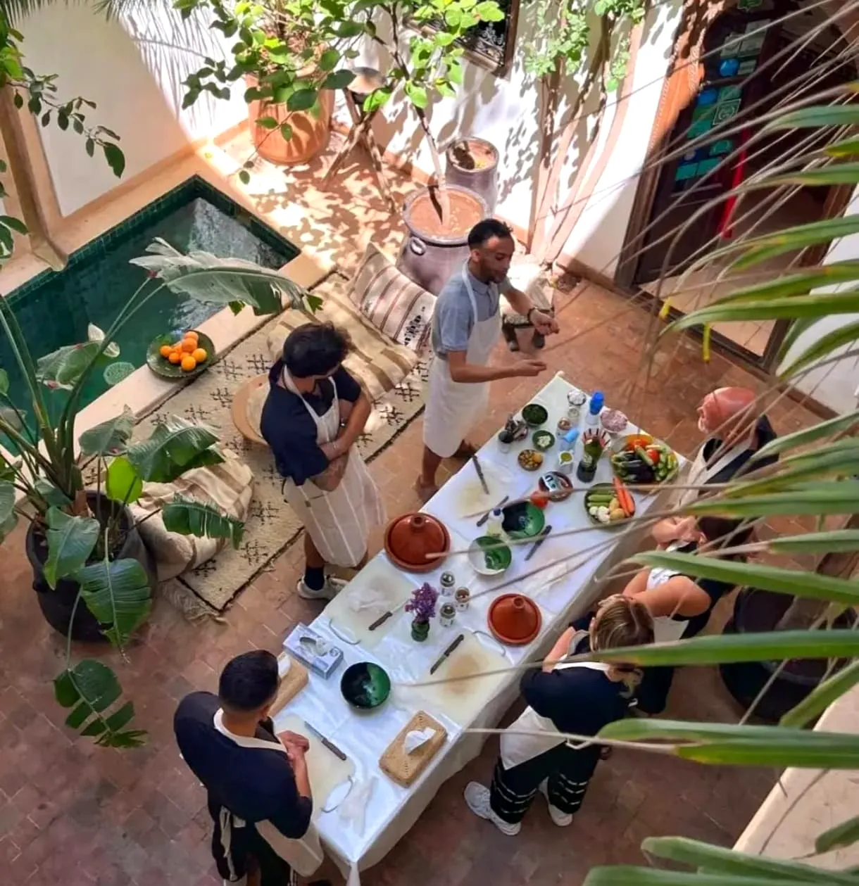Guests cooking around the class table in a Marrakech riad courtyard